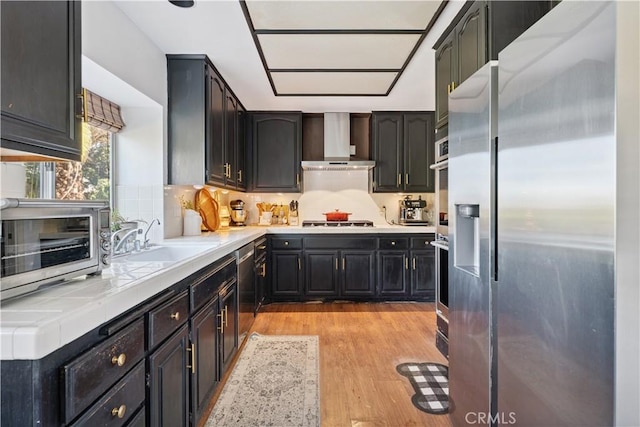 8042 Masefield Ct, West Hills, CA 91304 - kitchen featuring stainless steel appliances, wall chimney exhaust hood, tile countertops, light wood-style floors, and tasteful backsplash