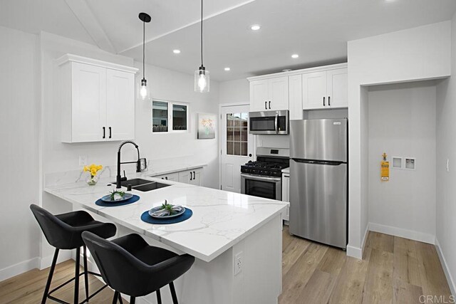 1254 13th St, Imperial Beach, CA 91932 - kitchen with appliances with stainless steel finishes, a peninsula, light wood finished floors, light stone counters, and white cabinets