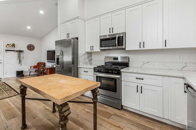 1254 13th St, Imperial Beach, CA 91932 - kitchen featuring appliances with stainless steel finishes, light wood finished floors, white cabinets, high vaulted ceiling, and light stone counters