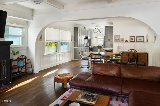 4207 Berenice Ave, Los Angeles, CA 90031 - living area featuring arched walkways, dark wood-style flooring, a decorative wall, beamed ceiling, and a wainscoted wall