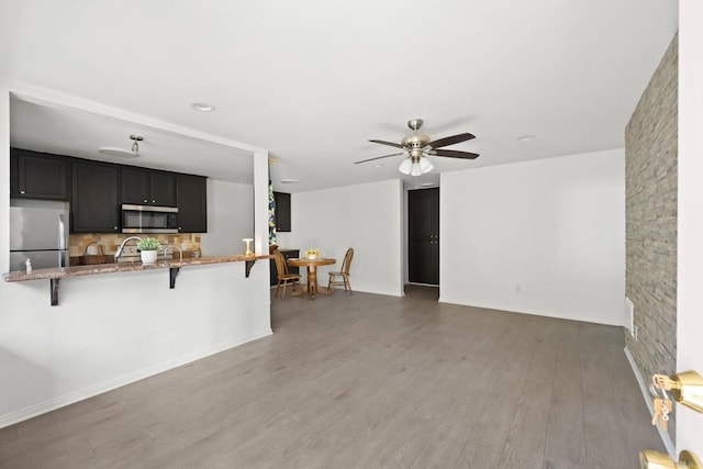 9860 Dale Ave Unit A8, Spring Valley, CA 91977 - kitchen with stainless steel appliances, a kitchen breakfast bar, stone countertops, a ceiling fan, and light wood-style flooring