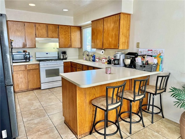 1602 W Dorothea Ave W, Visalia, CA 93277 - kitchen with stainless steel appliances, under cabinet range hood, a peninsula, brown cabinets, and light countertops
