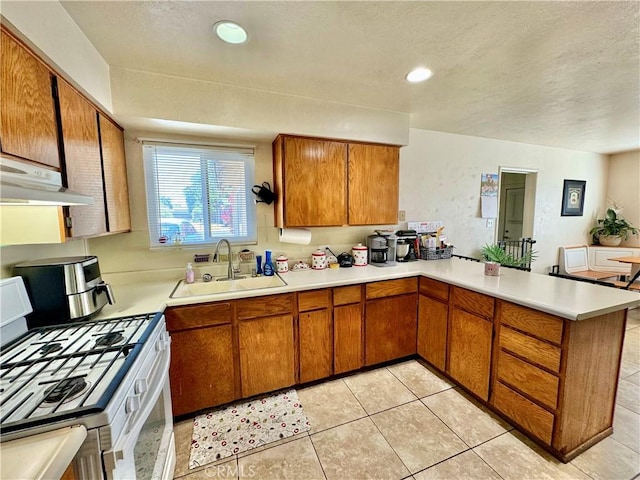 1602 W Dorothea Ave W, Visalia, CA 93277 - kitchen featuring white gas range oven, a peninsula, light countertops, brown cabinetry, and under cabinet range hood