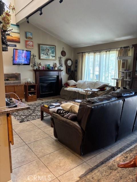 29441 Via La Plz, Murrieta, CA 92563 - living room featuring light tile patterned floors, vaulted ceiling, a fireplace, and track lighting