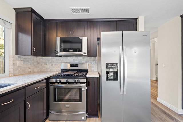 5149 Maplewood Cir, Oceanside, CA 92056 - kitchen with stainless steel appliances, dark brown cabinets, tasteful backsplash, light stone countertops, and light wood-type flooring