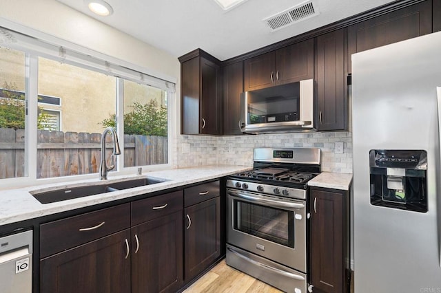 5149 Maplewood Cir, Oceanside, CA 92056 - kitchen with appliances with stainless steel finishes, light stone counters, dark brown cabinets, and tasteful backsplash