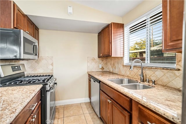 2017 W Newgrove St, Lancaster, CA 93536 - kitchen with stainless steel appliances, light tile patterned flooring, tasteful backsplash, light stone countertops, and brown cabinets
