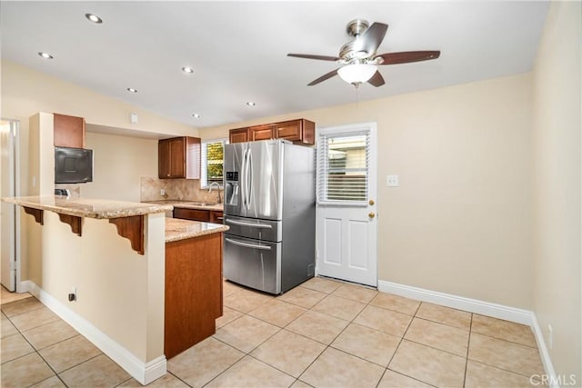 2017 W Newgrove St, Lancaster, CA 93536 - kitchen with stainless steel refrigerator with ice dispenser, a peninsula, a kitchen bar, backsplash, and light tile patterned flooring