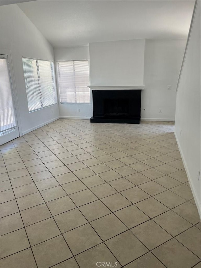 7711 Cartilla Ave, Fontana, CA 92336 - unfurnished living room featuring light tile patterned flooring, a fireplace with raised hearth, and vaulted ceiling
