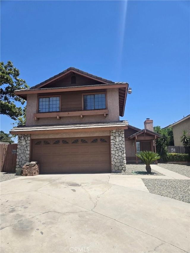 7711 Cartilla Ave, Fontana, CA 92336 - view of front of house with stucco siding, driveway, a garage, and stone siding