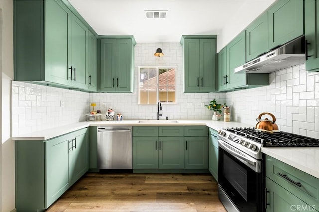 1030 Echo Park Ave, Los Angeles, CA 90026 - kitchen with stainless steel appliances, green cabinets, under cabinet range hood, light countertops, and tasteful backsplash