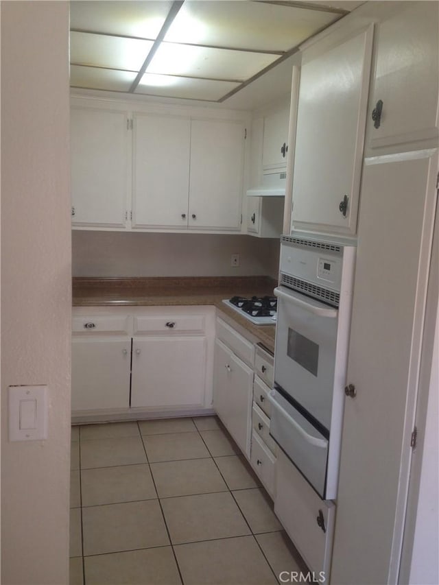 12071 Laguna St, Garden Grove, CA 92840 - kitchen with white appliances, a warming drawer, light tile patterned floors, white cabinetry, and range hood
