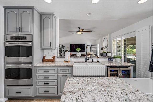 32175 Cedarcroft Rd, Acton, CA 93510 - kitchen with gray cabinetry, stainless steel double oven, beverage cooler, ceiling fan, and vaulted ceiling