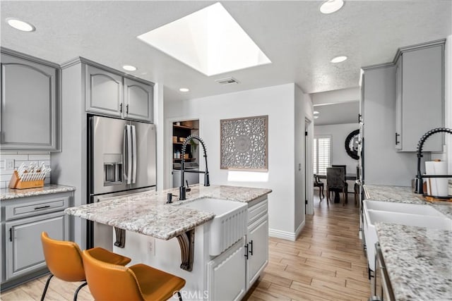 32175 Cedarcroft Rd, Acton, CA 93510 - kitchen featuring gray cabinetry, a skylight, light wood-style flooring, recessed lighting, and a center island with sink