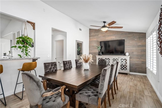 32175 Cedarcroft Rd, Acton, CA 93510 - dining room with lofted ceiling, wood walls, a ceiling fan, light wood-style floors, and an accent wall