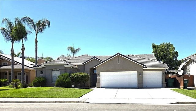 845 E Redwood Cir, Hanford, CA 93230 - view of front of home featuring a garage, stucco siding, driveway, a front lawn, and a tile roof
