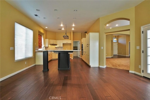 845 E Redwood Cir, Hanford, CA 93230 - kitchen featuring a center island, dark wood-style floors, white cabinetry, arched walkways, and recessed lighting