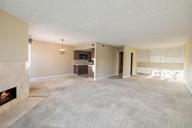 5870 Green Valley Cir Unit 231, Culver City, CA 90230 - unfurnished living room featuring a fireplace, light colored carpet, a textured ceiling, and a chandelier