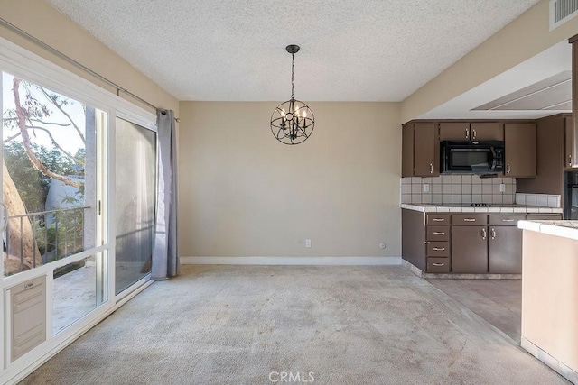 5870 Green Valley Cir Unit 231, Culver City, CA 90230 - kitchen featuring black microwave, a textured ceiling, decorative backsplash, light colored carpet, and tile counters
