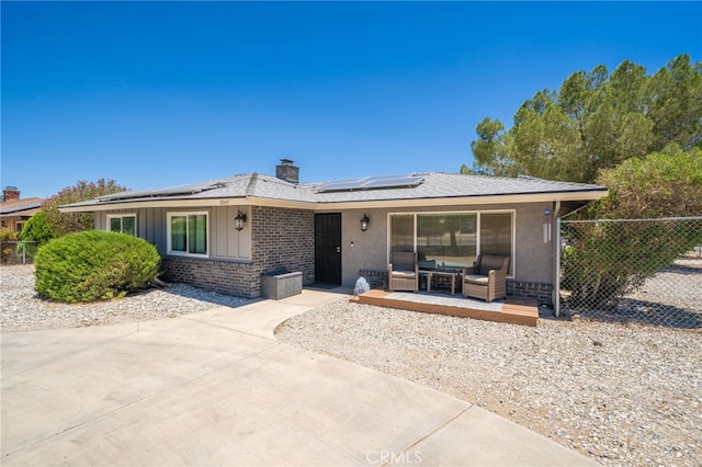 10147 Primrose Ave, Hesperia, CA 92345 - view of front of property with roof mounted solar panels, a chimney, brick siding, and outdoor lounge area