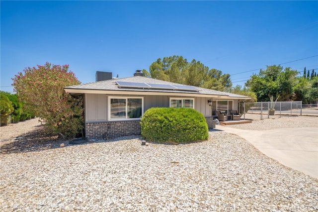 10147 Primrose Ave, Hesperia, CA 92345 - bungalow with board and batten siding, roof mounted solar panels, brick siding, and a chimney