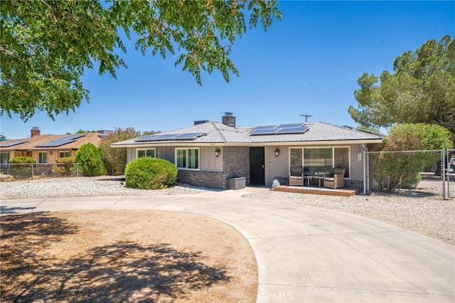 10147 Primrose Ave, Hesperia, CA 92345 - view of front facade featuring brick siding, roof mounted solar panels, a chimney, and curved driveway