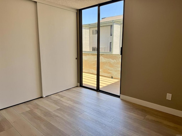6182 Agee St Unit 193, San Diego, CA 92122 - empty room featuring light wood-style flooring, expansive windows, and a textured ceiling