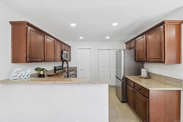 6876 Bear River Row Unit 3, San Diego, CA 92139 - kitchen featuring stainless steel appliances, a peninsula, light wood finished floors, recessed lighting, and light stone countertops