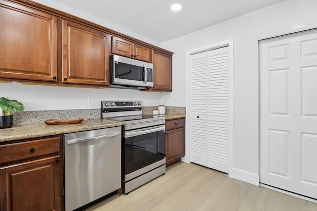 6876 Bear River Row Unit 3, San Diego, CA 92139 - kitchen featuring appliances with stainless steel finishes, light wood-type flooring, recessed lighting, brown cabinetry, and light stone counters