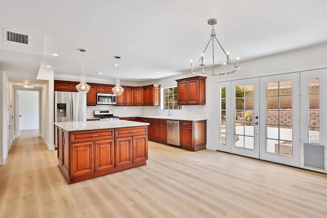 286 E Mission Rd, Corona, CA 92879 - kitchen with stainless steel appliances, light wood-style flooring, french doors, hanging light fixtures, and decorative backsplash