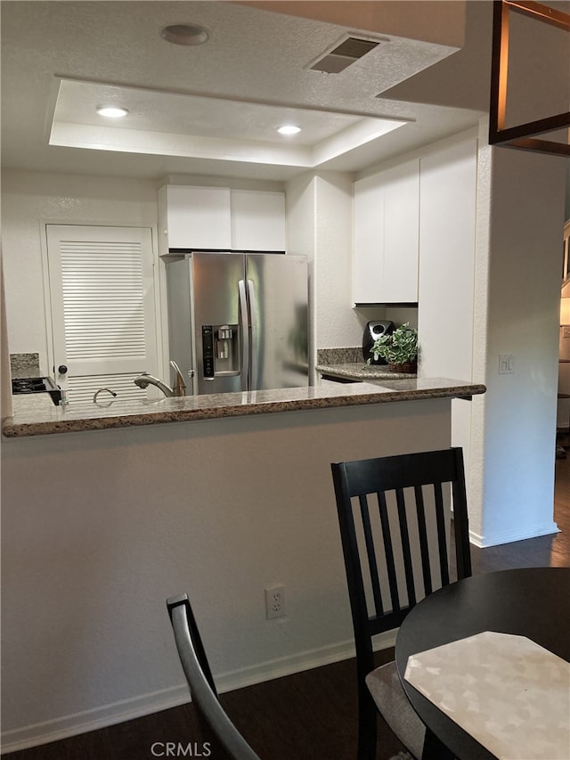 132 Sandpiper Ln, Aliso Viejo, CA 92656 - kitchen with a tray ceiling, stainless steel refrigerator with ice dispenser, white cabinets, recessed lighting, and stone countertops