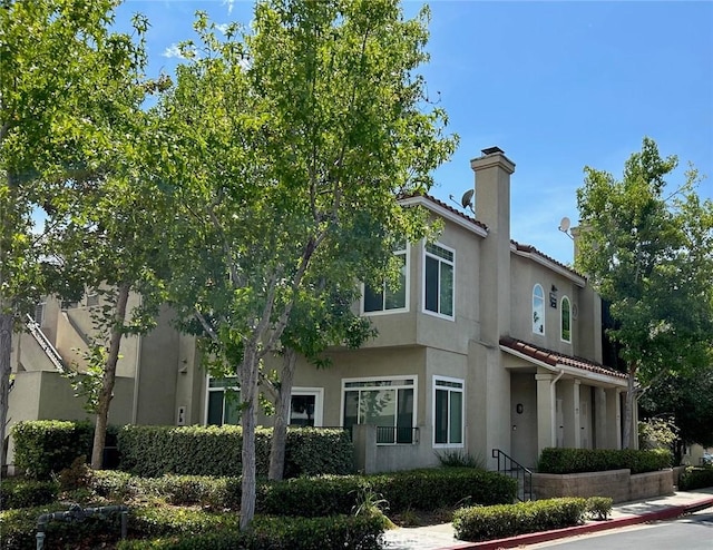 132 Sandpiper Ln, Aliso Viejo, CA 92656 - view of front facade with a chimney, a tiled roof, and stucco siding