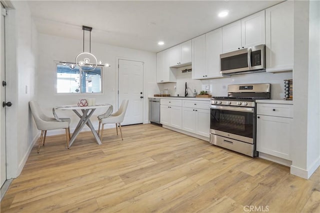 8283 Cornwall Ave, Rancho Cucamonga, CA 91739 - kitchen with stainless steel appliances, light wood finished floors, white cabinets, a chandelier, and recessed lighting