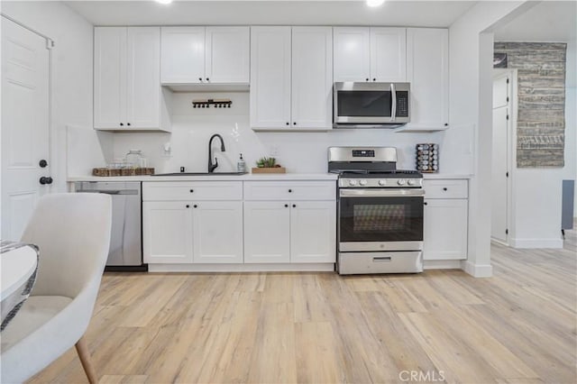 8283 Cornwall Ave, Rancho Cucamonga, CA 91739 - kitchen with appliances with stainless steel finishes, white cabinets, light wood-type flooring, and light countertops