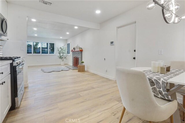 8283 Cornwall Ave, Rancho Cucamonga, CA 91739 - kitchen with stainless steel appliances, recessed lighting, light wood-style flooring, white cabinets, and a chandelier