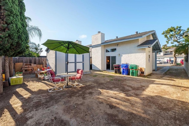 3833 Via Del Bardo, San Ysidro, CA 92173 - back of house featuring a shed, stucco siding, a fenced backyard, and a chimney