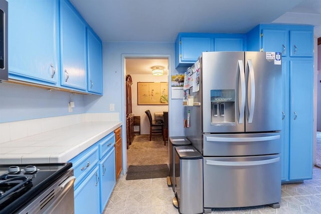 3833 Via Del Bardo, San Ysidro, CA 92173 - kitchen featuring appliances with stainless steel finishes, blue cabinetry, tile counters, and light tile patterned floors