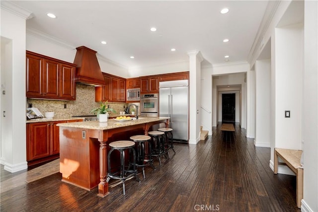 25 Thalia St, Ladera Ranch, CA 92694 - kitchen with built in appliances, dark wood-type flooring, an island with sink, backsplash, and a breakfast bar