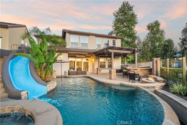 25 Thalia St, Ladera Ranch, CA 92694 - back of house at dusk featuring area for grilling, stucco siding, a patio area, a fire pit, and a pergola
