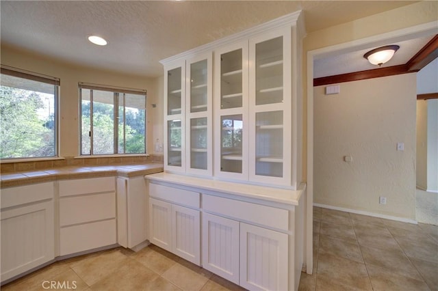 6305 Portola Rd, Atascadero, CA 93422 - kitchen with a textured ceiling, white cabinetry, glass insert cabinets, light tile patterned floors, and tile counters