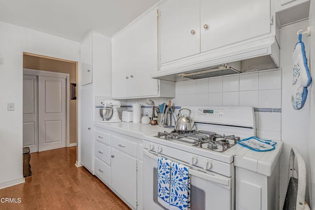 1373 Calle Crisantemo, Thousand Oaks, CA 91360 - kitchen featuring white gas stove, tile countertops, white cabinets, light wood finished floors, and decorative backsplash