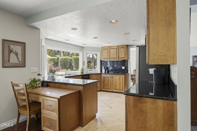 2142 Klamath Dr, Camarillo, CA 93010 - kitchen featuring brown cabinetry, a peninsula, backsplash, a textured ceiling, and dark stone counters