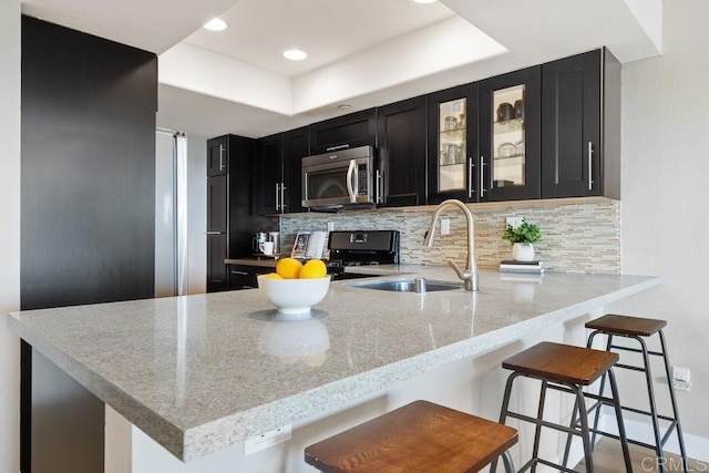 183 Mangano Cir, Encinitas, CA 92024 - kitchen with stainless steel microwave, dark cabinetry, tasteful backsplash, a peninsula, and a tray ceiling