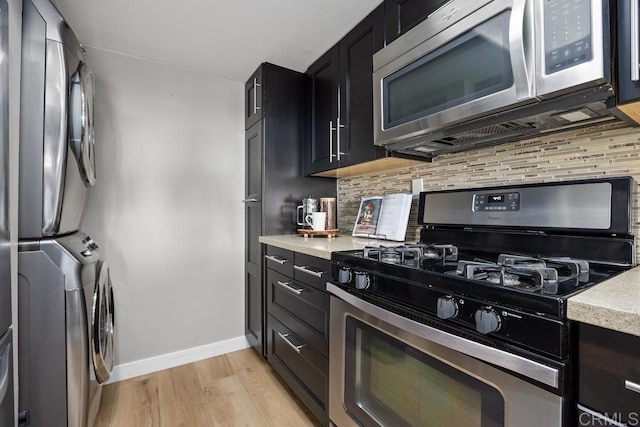 183 Mangano Cir, Encinitas, CA 92024 - kitchen featuring stainless steel appliances, stacked washing machine and dryer, decorative backsplash, light wood finished floors, and dark cabinets