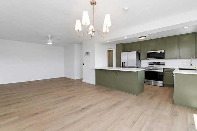 615 Fredricks Ave Unit 157, Oceanside, CA 92058 - kitchen with appliances with stainless steel finishes, green cabinetry, a peninsula, light countertops, and light wood finished floors