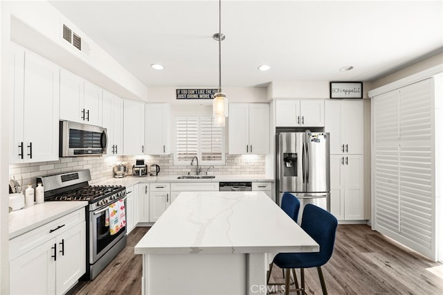 11209 Pinecone St, Corona, CA 92883 - kitchen with stainless steel appliances, a kitchen breakfast bar, dark wood-style floors, tasteful backsplash, and a center island