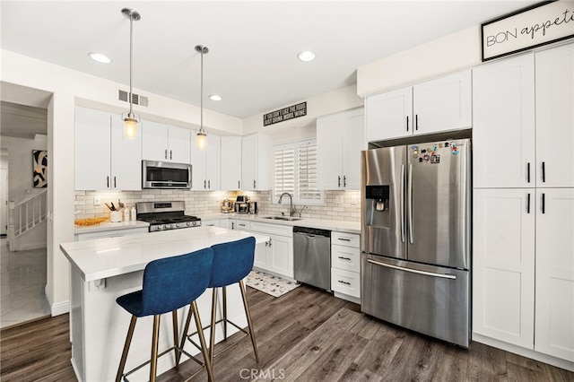 11209 Pinecone St, Corona, CA 92883 - kitchen with appliances with stainless steel finishes, backsplash, a breakfast bar, white cabinetry, and recessed lighting