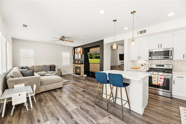 11209 Pinecone St, Corona, CA 92883 - kitchen with appliances with stainless steel finishes, a breakfast bar, wood finished floors, tasteful backsplash, and a center island