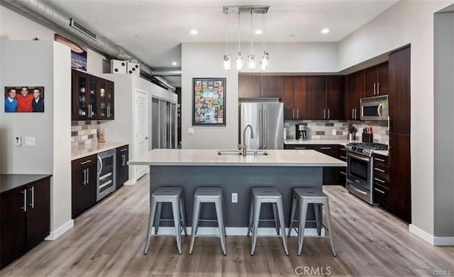 133 The Promenade N Unit 317, Long Beach, CA 90802 - kitchen featuring stainless steel appliances, decorative backsplash, a kitchen bar, an island with sink, and light wood-type flooring