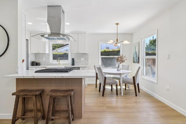 8450 Dallas St, La Mesa, CA 91942 - kitchen featuring island exhaust hood, white cabinets, plenty of natural light, light countertops, and recessed lighting